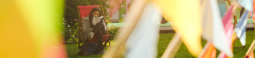 A women sitting on a deck chair in the sunshine at the Hay Festival.